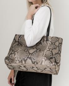 Female model against white background in white sweater and black jeans wearing snake skin B. May handbag