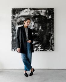 Woman model standing in front of black painting wearing black Nellie Partow