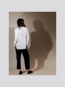 Back of model wearing white top and black pants